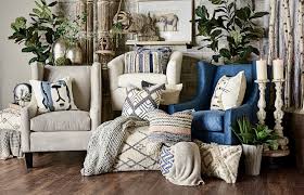"A stylish collection of home accessories, including decorative throw pillows, a ceramic vase with fresh flowers, a cozy knit blanket, scented candles, and framed art prints arranged on a modern coffee table