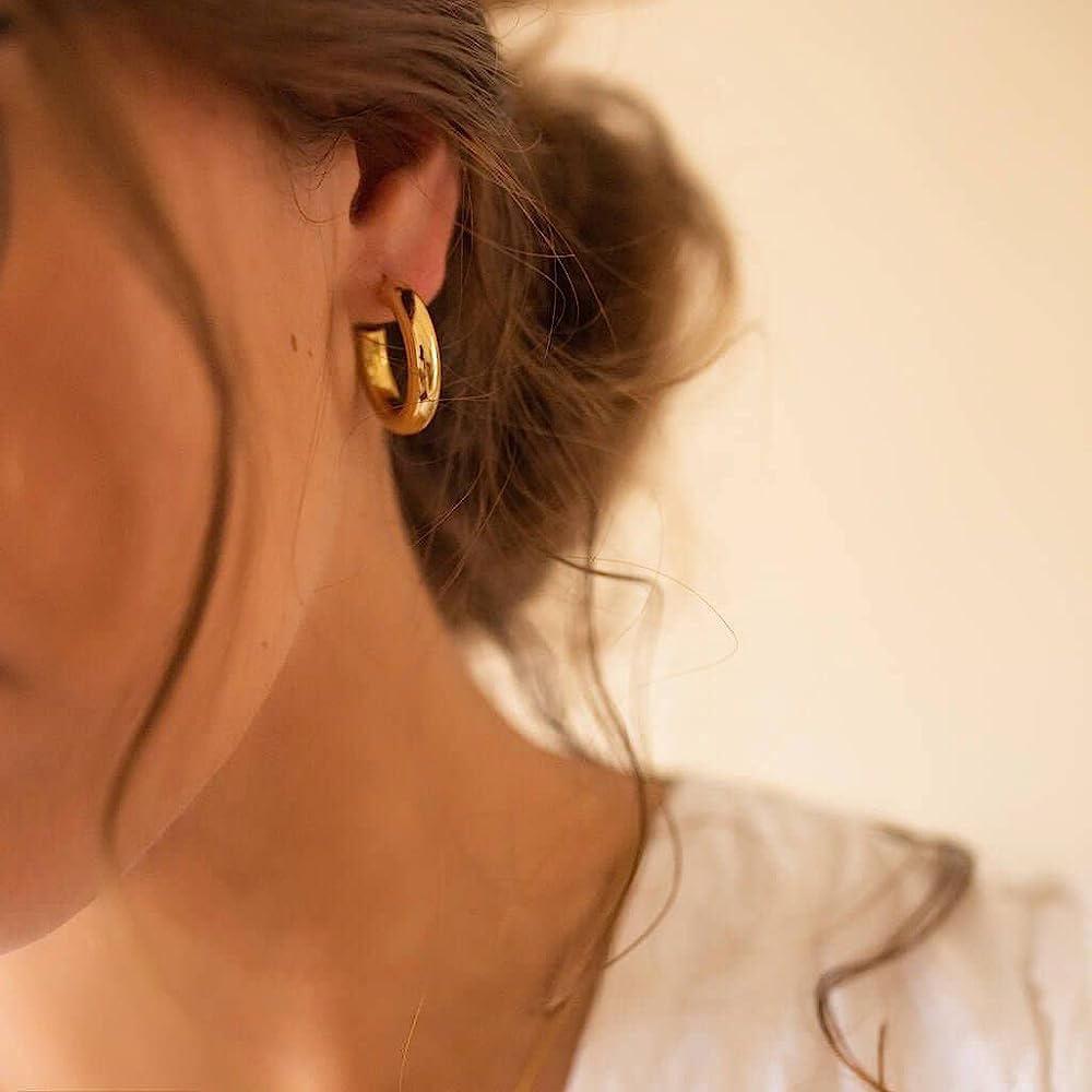 A pair of stylish earrings featuring a detailed design, including a combination of gemstones or pearls set in a metal framework, displayed against a soft background to emphasize their elegance and craftsmanship.